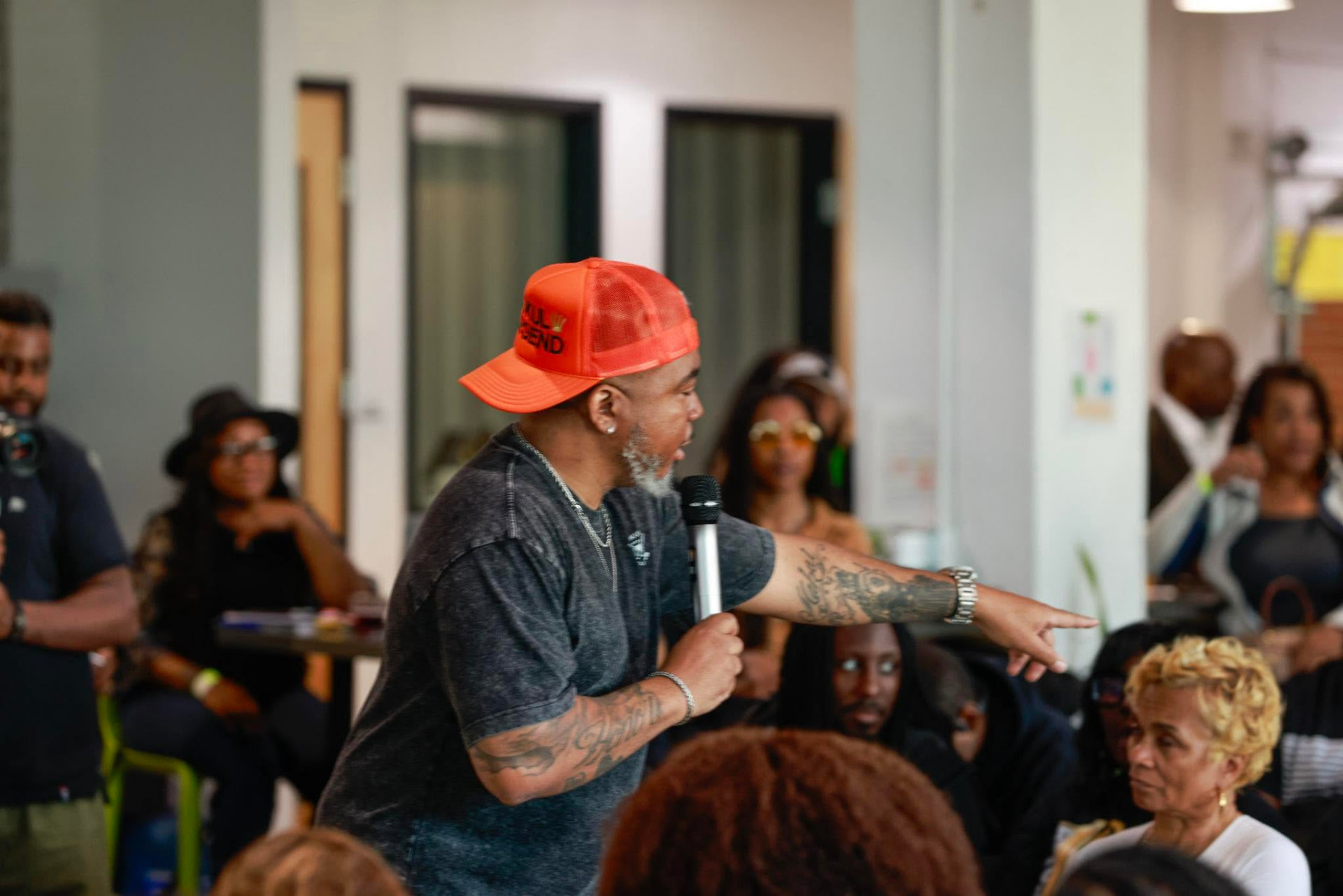 Jay.R Fogle holding a microphone and pointing at a crowd during a workshop
